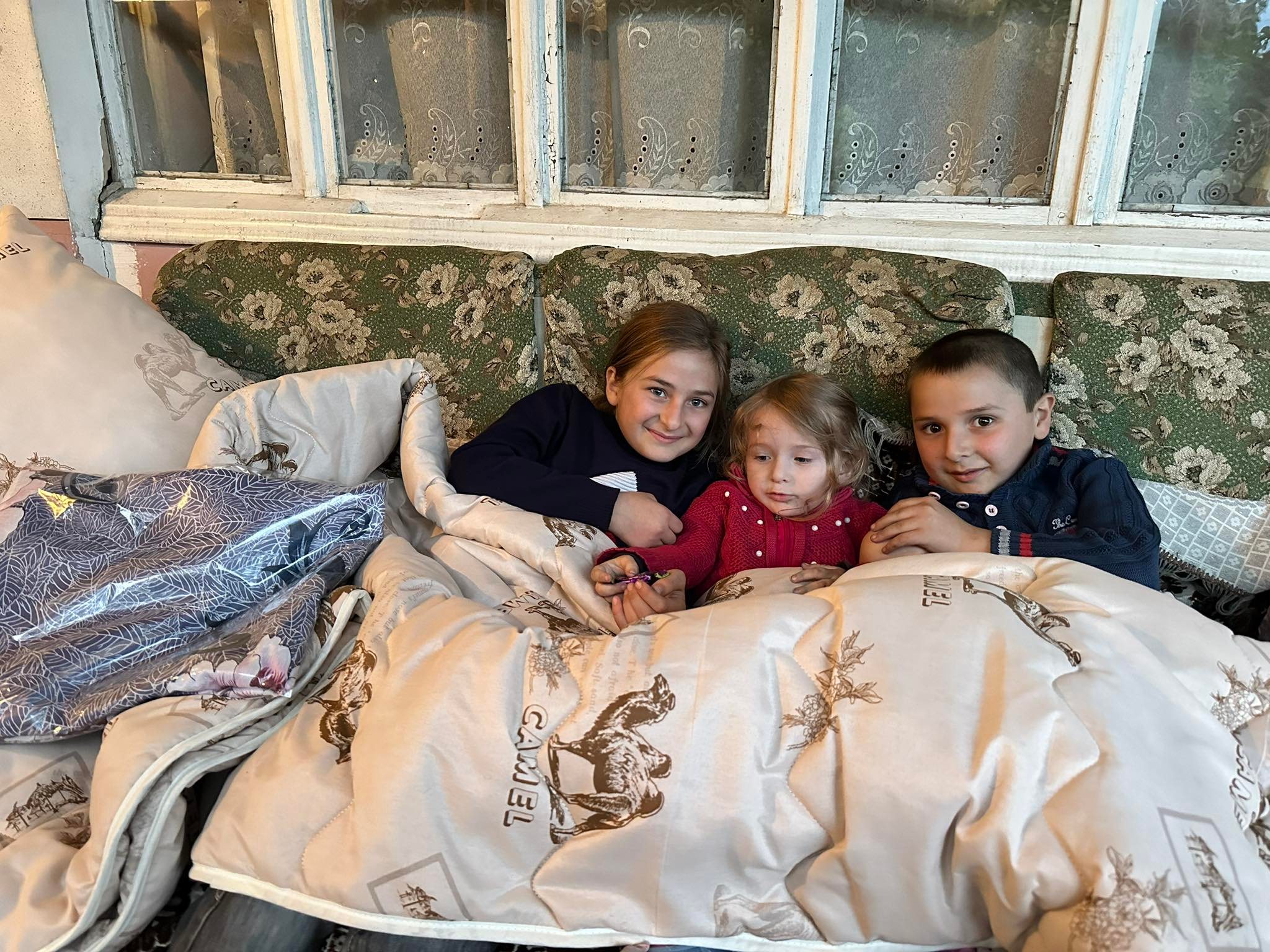 Refugee%20children%20cuddling%20up%20under%20warm%20blankets%20on%20new%20beds